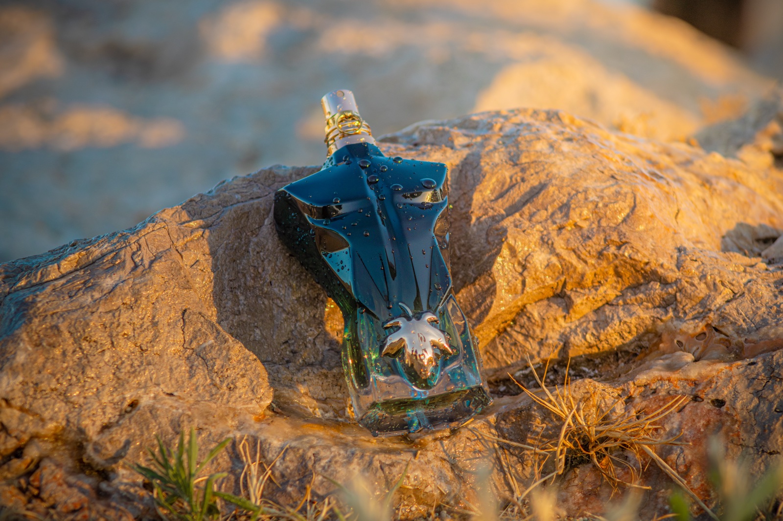 Foto editada: frasco de perfume sobre una roca al atardecer