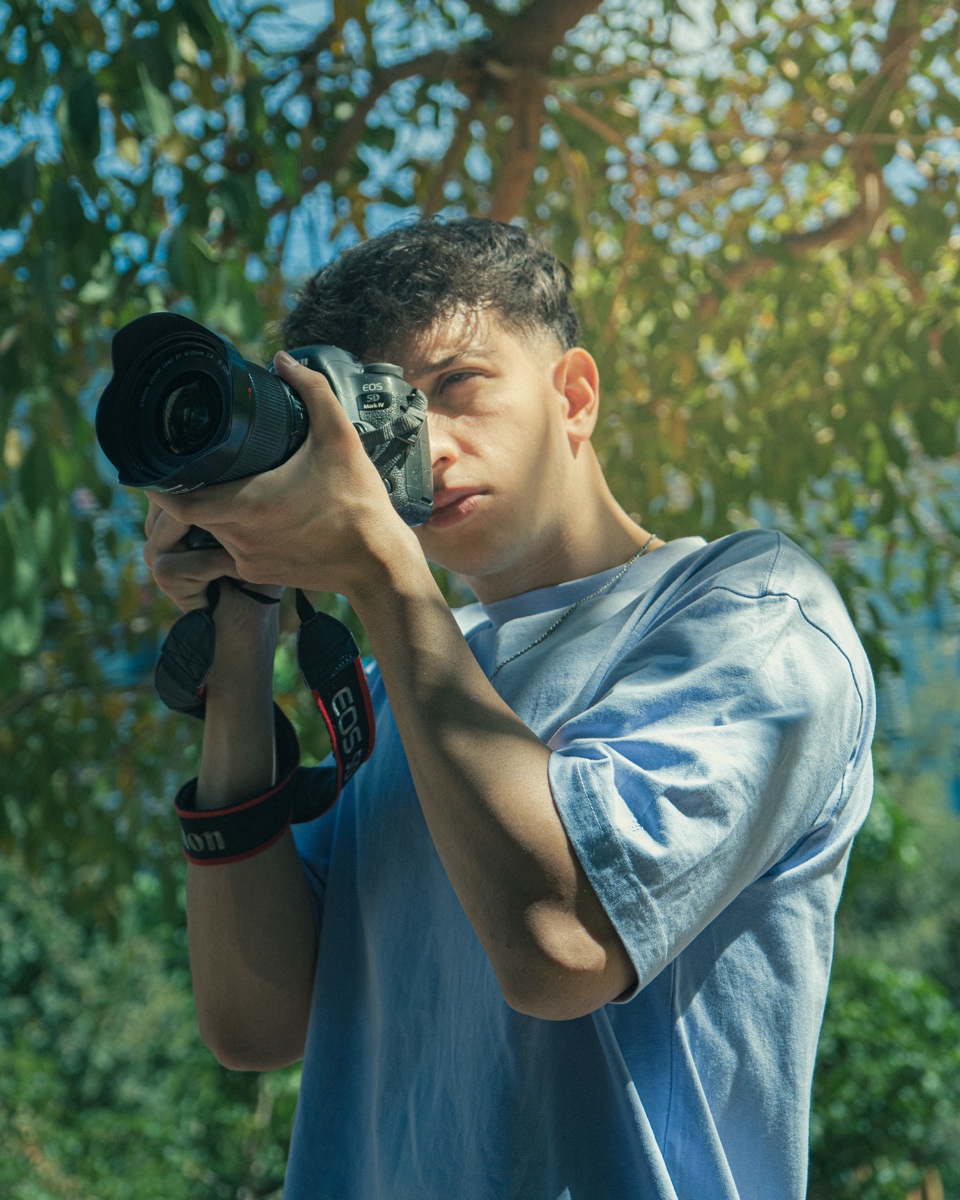 Stefano Aiosa fotografiando con su cámara bajo un árbol